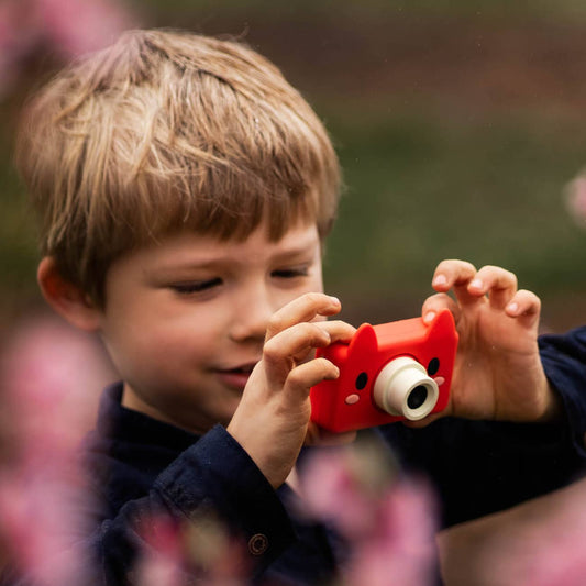 Boy holding fox-shaped kids' digital camera in orange color