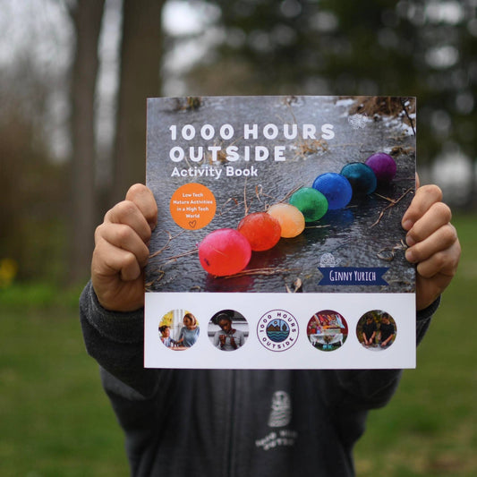 1000 Hours Outside Book being held by a person out of focus from the camera.