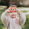 Child holding Fox-shaped kids' digital camera in orange color