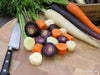 Bunch of multicolored carrots on a cutting board- purple, orange, and white
