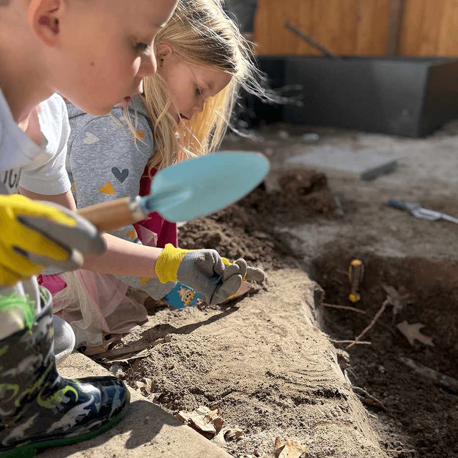 Two children playing with gardening tools in a garden